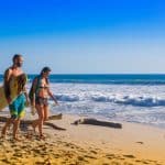 Santa Teresa, Costa Rica - surfers walking on the beachJune, 28, 2018: Couple of surfers on the beach of Santa Teresa walking and enjoying the time together in a beautiful sunny day with blue sky and blue water